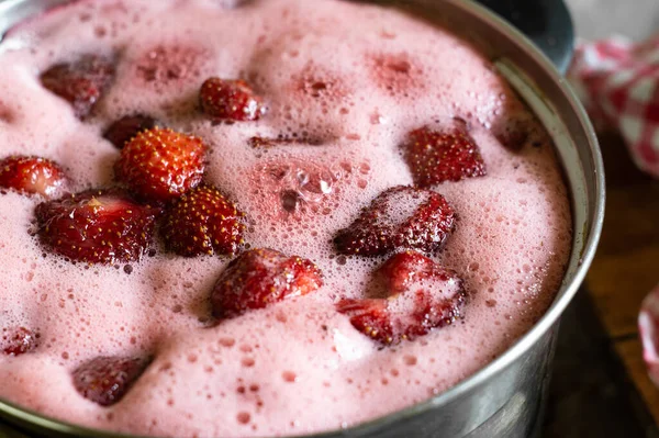 Çilek reçeli pişiriyorum. Tavada kaynamış şekerli meyveler köpük oluşturur.