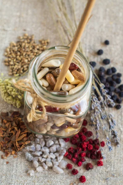 Bitkisel ve mineral içeren kapsüller cam kavanozda ve malzemelerde organik besin takviyeleri. Vitaminler ve biyokatkı maddeleri