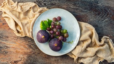 İncir ve üzümler ahşap bir masada.