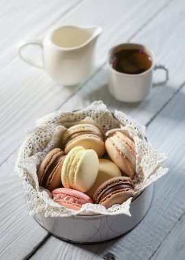 Dantelli bir tabakta çok renkli makaronlar ve bir fincan kahve.