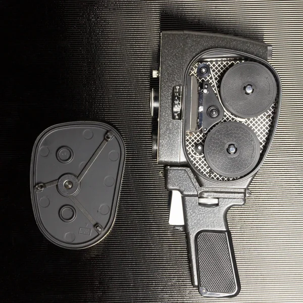 Açık kapaklı ve siyah arkaplanlı eski amatör film kamerası.