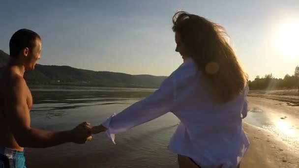 Ein Mädchen und ein Mann, die am Strand herumlaufen — Stockvideo