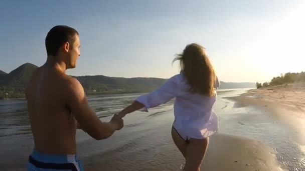 Una chica y un chico corriendo por la playa — Vídeos de Stock