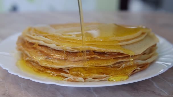 Pannenkoeken op een bord zijn gevuld met honing — Stockvideo