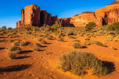 Arizona 'daki Navajo kabile parkındaki Anıt Vadisi' nin manzaralı kuleleri ve kızıl kaya çölü güçlü güneş ışığı altında Amerika Birleşik Devletleri..