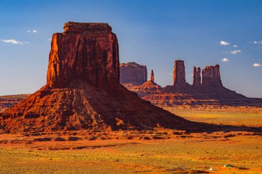 Arizona 'daki Navajo kabile parkındaki Anıt Vadisi' nin manzaralı kuleleri ve kızıl kaya çölü güçlü güneş ışığı altında Amerika Birleşik Devletleri..