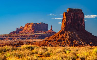 Arizona 'daki Navajo kabile parkındaki Anıt Vadisi' nin manzaralı kuleleri ve kızıl kaya çölü güçlü güneş ışığı altında Amerika Birleşik Devletleri..