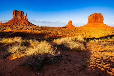 Arizona 'daki Navajo kabile parkındaki Anıt Vadisi' nin manzaralı kuleleri ve kızıl kaya çölü güçlü güneş ışığı altında Amerika Birleşik Devletleri..