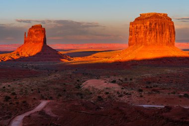 Batı ve Doğu Mitten Buttes (Mittens olarak da bilinir) Arizona 'daki Navajo Anıt Vadisi Kabile Parkı' nda güneşle aydınlanan iki kıç..