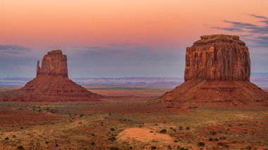Batı ve Doğu Mitten Buttes Anıt Vadisi Navajo Kabile Parkı 'nda (ayrıca Mitten olarak da bilinir) alacakaranlıkta Utah' ta gün batımında.