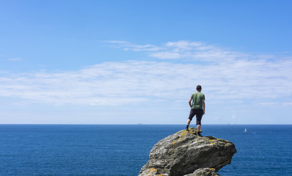 Man on top of rock, looking at sea
