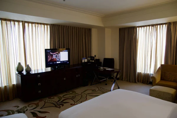 DUBAI, UNITED ARAB EMIRATES - JUN 16, 2019: Een bureau in een luxe business hotel kamer met een tv en bed op de voorgrond — Stockfoto