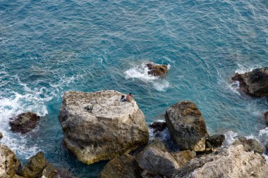MELLIEHA, MALTA - 01 Ocak 2020: Sakin deniz sırasında Malta adasındaki bir kayanın üzerinde oturan bir adam