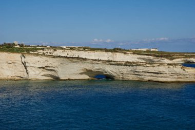 DELIMARA, MARSAXLOKK, MALTA - 03 HAZİRAN, 2020: Delimara Malta 'da küçük bir körfezin kıyıları ve kıyıları, yazın güneşli bir günde mavi gökyüzü ve limon taşı kıyıları boyunca Akdeniz boyunca uzanan mavi turkuaz denizi