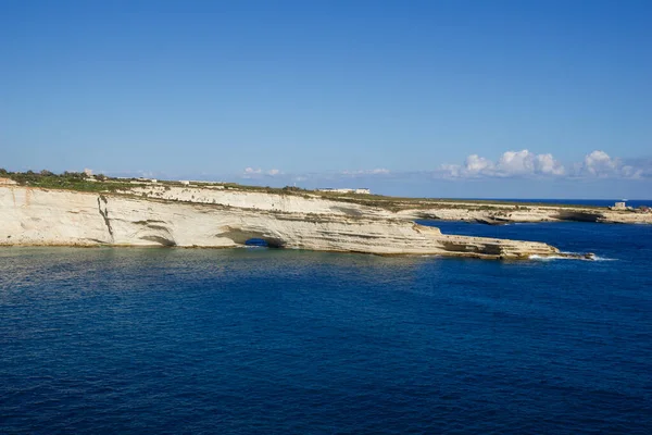 DELIMARA, MARSAXLOKK, MALTA - 03 HAZİRAN, 2020: Delimara Malta 'da küçük bir körfezin kıyıları ve kıyıları, yazın güneşli bir günde mavi gökyüzü ve limon taşı kıyıları boyunca Akdeniz boyunca uzanan mavi turkuaz denizi