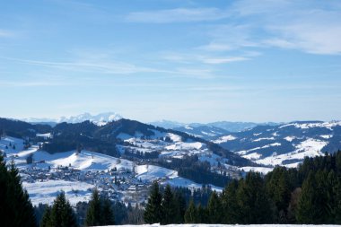 OBERSTAUFEN, GERMANY - 29 DEC, 2017: Bavyera Alplerinde yeşil kozalaklı ağaçlarla karla kaplı Oberstaufen kış spor merkezinin harika manzarası