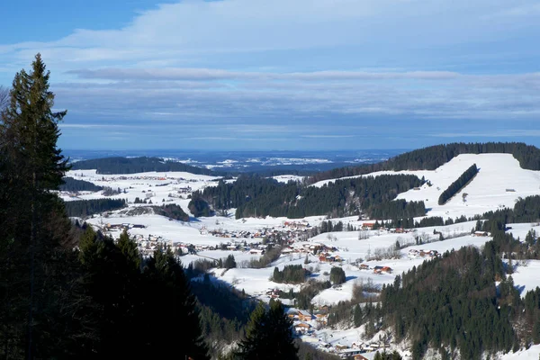 OBERSTAUFEN, ALLEMAGNE - 29 DEC, 2017 : Magnifique vue sur la station de sports d'hiver enneigée d'Oberstaufen dans les Alpes bavaroises avec des conifères verts au premier plan — Photo