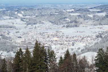 OBERSTAUFEN, GERMANY - 29 DEC, 2017: Bavyera Alplerinde yeşil kozalaklı ağaçlarla karla kaplı Oberstaufen kış spor merkezinin harika manzarası