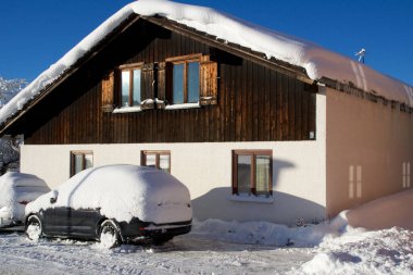 OBERSTAUFEN, ALMANY - 29 ARALIK, 2017: Kışın Alman Alpleri 'ndeki tipik ahşap ev çatısı karla kaplı ve önünde karla kaplı bir araba
