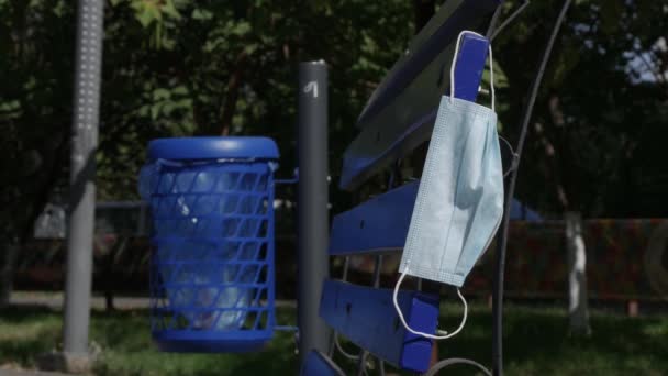 Medical Face Mask Used and Abandoned on a Bench in Park, Dangerous Garbage Infected with Coronavirus — Stock Video