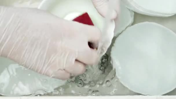 Mãos de empregada usando luvas de proteção Enxaguar os pratos na pia com água Usando uma esponja de lavagem de louça — Vídeo de Stock