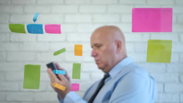 Immagine sfocata con un uomo d'affari che parla con il telefono cellulare e fa gesti sul retro di una scheda trasparente con appunti appiccicosi — Video Stock