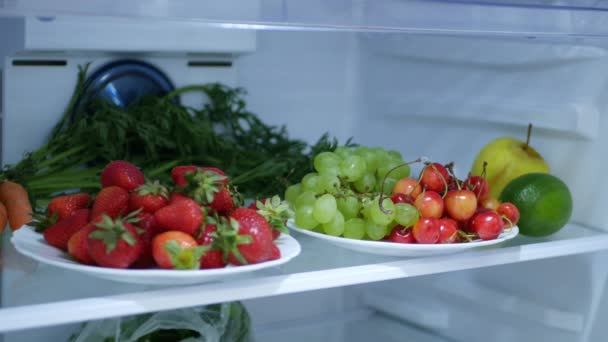 Tiro con fresas frescas y frías, cerezas y uvas en un refrigerador de cocina — Vídeo de stock