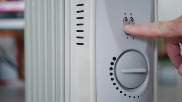 Человек устанавливает температуру нагрева электрического радиатора дома — стоковое видео