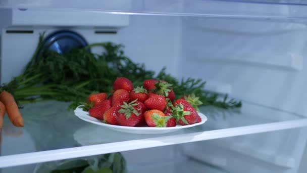 Tiro con fresas frescas y frías en un plato en un refrigerador de cocina — Vídeo de stock