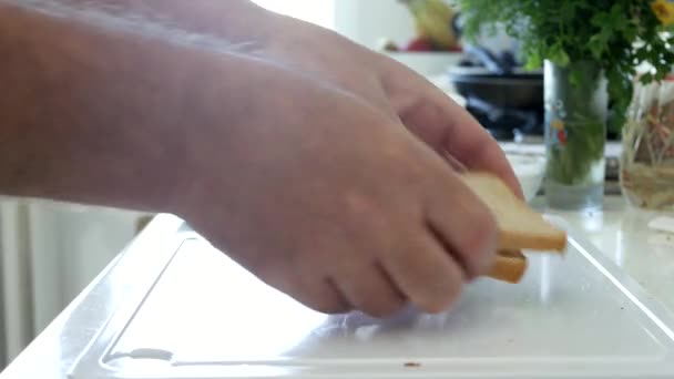 Homem na cozinha organizar sobre a mesa duas fatias de pão para um sanduíche — Vídeo de Stock