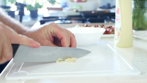 Man in de keuken knoflook hakken op een aanrecht — Stockvideo