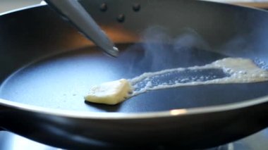 Sıcak tavada bir sürü dumanla erimiş yağlı tereyağı.