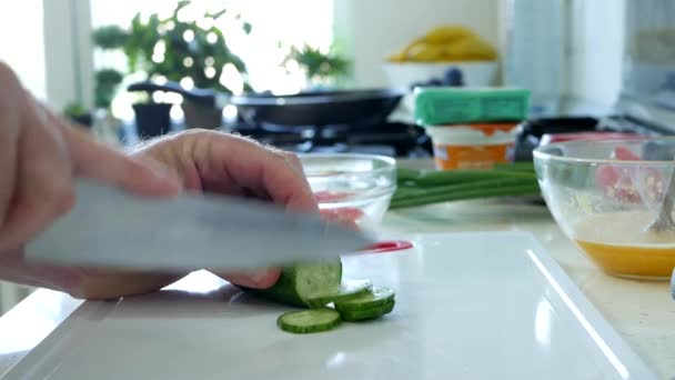 Mann in der Küche schneidet frische Gurken für Salat — Stockvideo