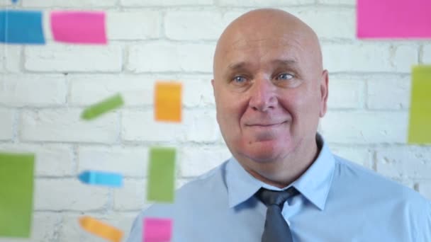 Empresário Sorriso por trás de uma placa transparente com notas adesivas coloridas na sala de reuniões — Vídeo de Stock