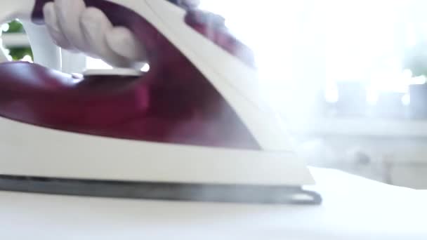 Die Tätigkeit einer Haushälterin, die saubere Wäsche mit elektrischem Bügeleisen und heißem Dampf bügelt — Stockvideo