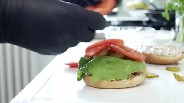 A séf ízletes hamburgert készít hússal, sajttal és zöldséggel — Stock videók