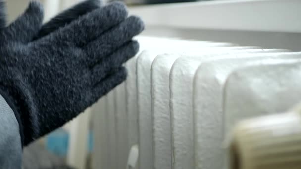 Persona congelada con guantes de punto en las manos Trate de calentarse cerca de un radiador — Vídeos de Stock