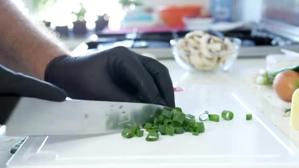 Homem na cozinha cortando cebola fresca primavera para uma salada — Vídeo de Stock