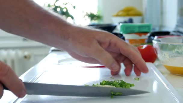 Muž v kuchyni krájí jarní cibuli na salát — Stock video