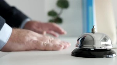 Otel resepsiyonunda kapı anahtarını alan resepsiyonisti bekleyen bir turist.
