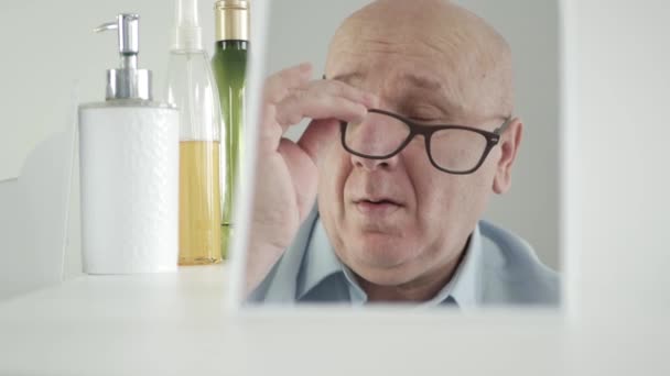 Mężczyzna przed lustrem w łazience zdejmuje okulary i masuje zmęczone oczy — Wideo stockowe