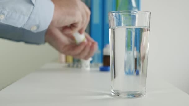 Больной человек, страдающий от большой головной боли, кладет в стакан с водой блестящую таблетку — стоковое видео