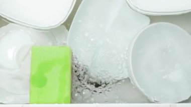 Yıkanmaya ve durulamaya hazır bir lavaboda bulaşıklar.