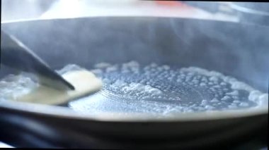 Kahvaltı hazırlamak için mutfağın fırınında sıcak tavada erimiş tereyağı.