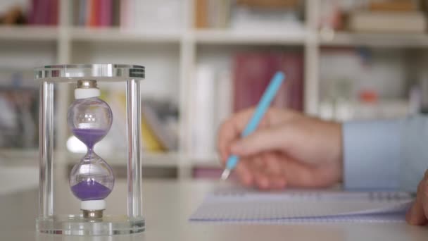 Hourglass робить час іспиту. Студент написав тест розмитим у тлі . — стокове відео