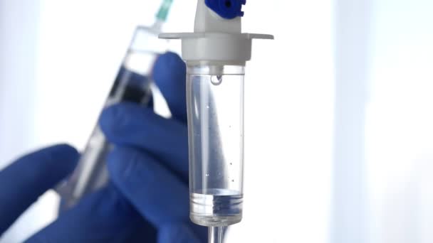 Une perfusion goutte à goutte et un médecin préparant une seringue avec un vaccin, floue en arrière-plan. — Video