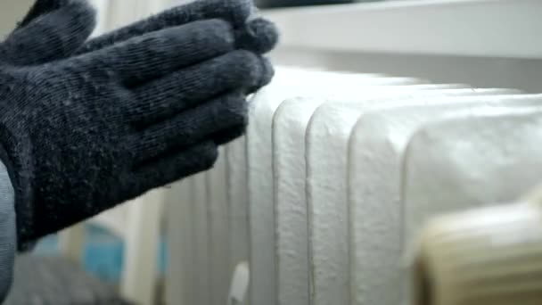 Persona congelada con guantes de punto en las manos Trate de calentarse cerca de un radiador — Vídeo de stock