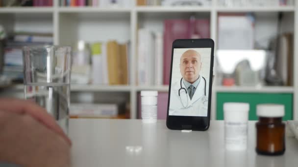 Homme avec un téléphone cellulaire Parlez avec un médecin au sujet des médicaments à l'aide d'une application médicale par vidéoconférence. Distanciation sociale en cas de pandémie. — Video