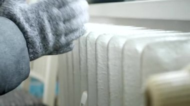 Ellerinde eldiven olan Donmuş Kişi Radyatörün yanında Isınmaya Çalışıyor