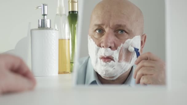 Biznesmen rano patrzy w lustro łazienki i goli brodę — Wideo stockowe